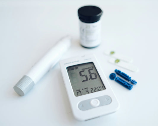 A blood glucose meter with a lancing device and test strips on white