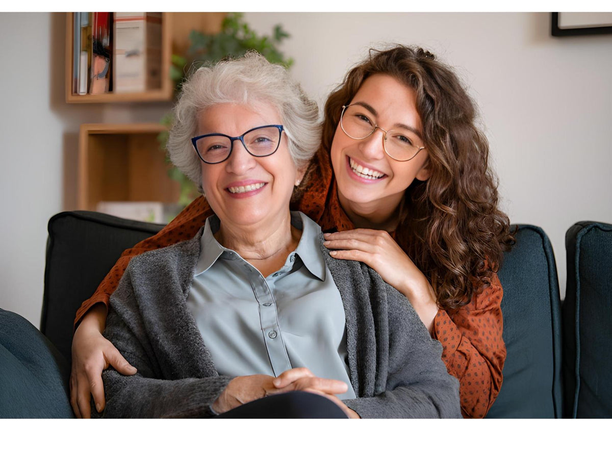 Two women sitting together on a couch, smiling and embracing.